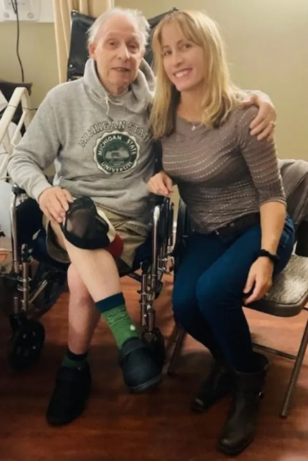 two individuals sitting closely, one with a prosthetic leg and the other in jeans