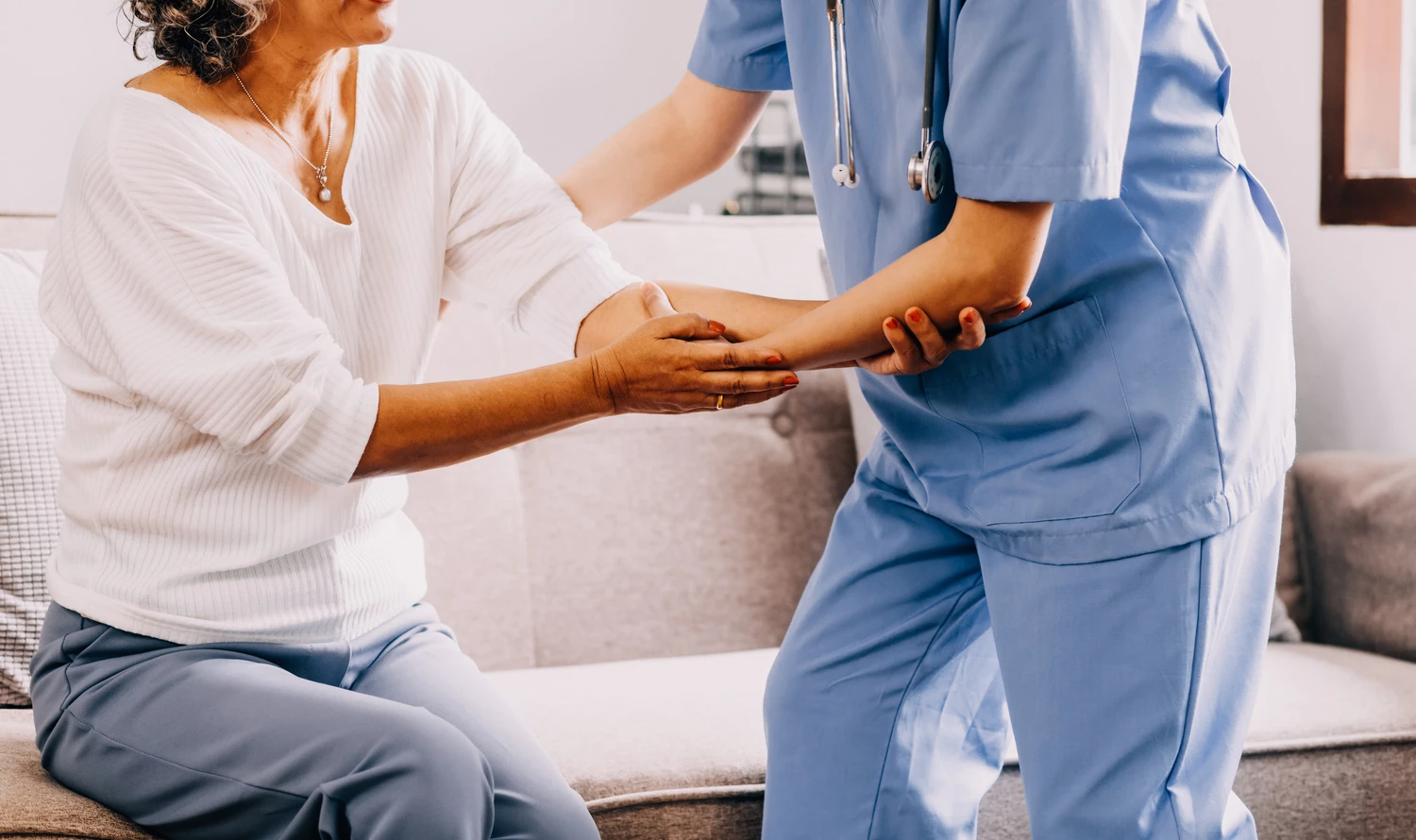 Happy young female nurse provide care medical service help support smiling old grandma at homecare medical visit